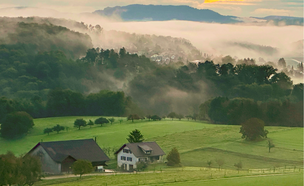 Village surrounded by hills with clouds